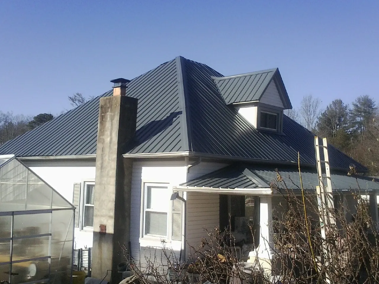 Dark blue standing seam metal roof on a white farmhouse with dormer — Slate & Tile Roof Repair by Roofing Brothers in Saratoga
