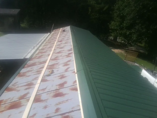 Old rusted panels beside newly installed green metal roofing — Wind Damage Roof Repair by Roofing Brothers in Saratoga