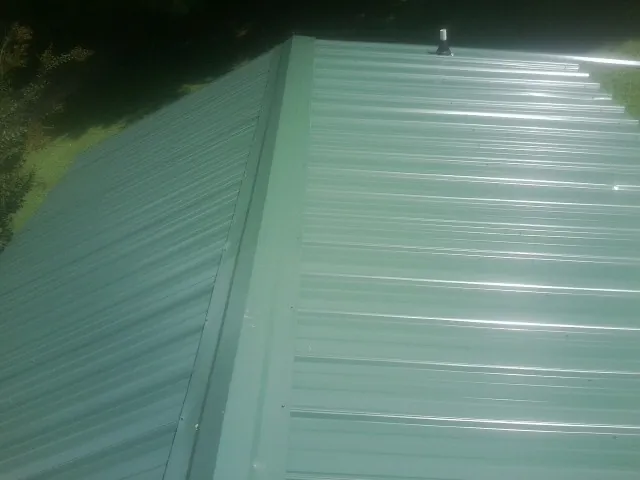 New green metal panels meeting at the ridge of a roof — Flat Roof Repair work by our crew in Saratoga
